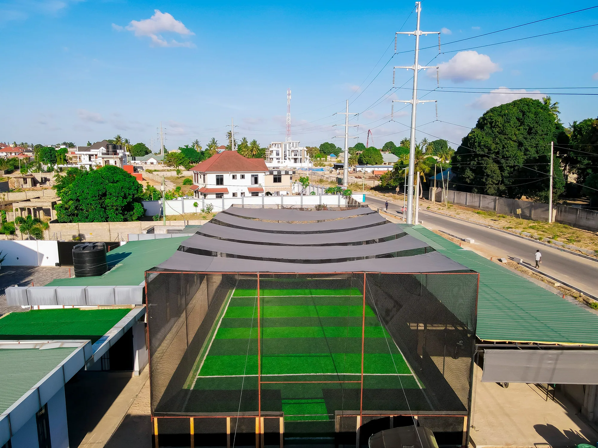 Front aerial view of the netted Kibada Soccer Pitch and shade canopy
